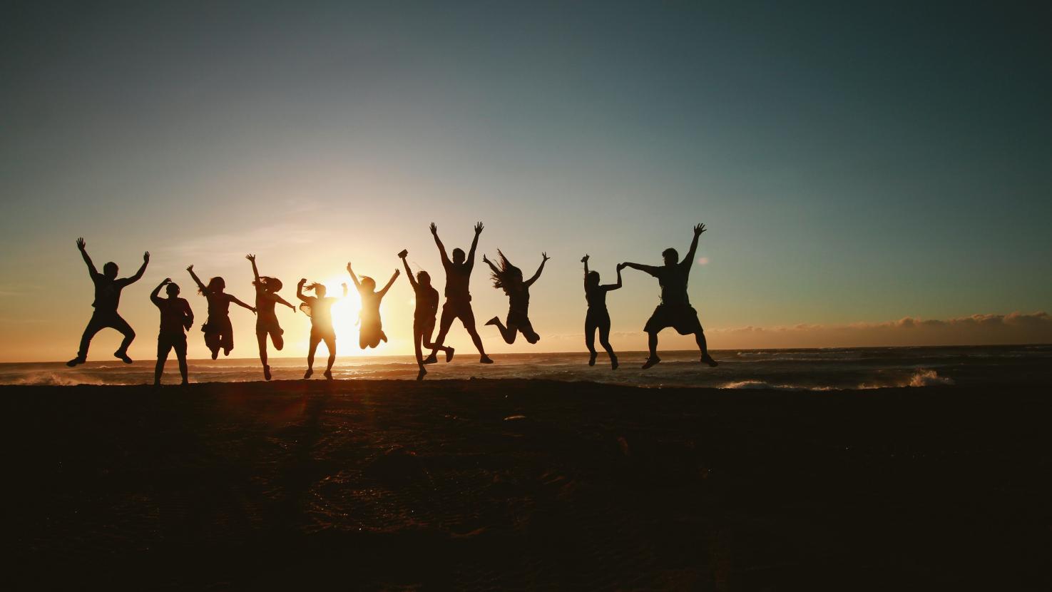 Group of people jumping in the air at sunset