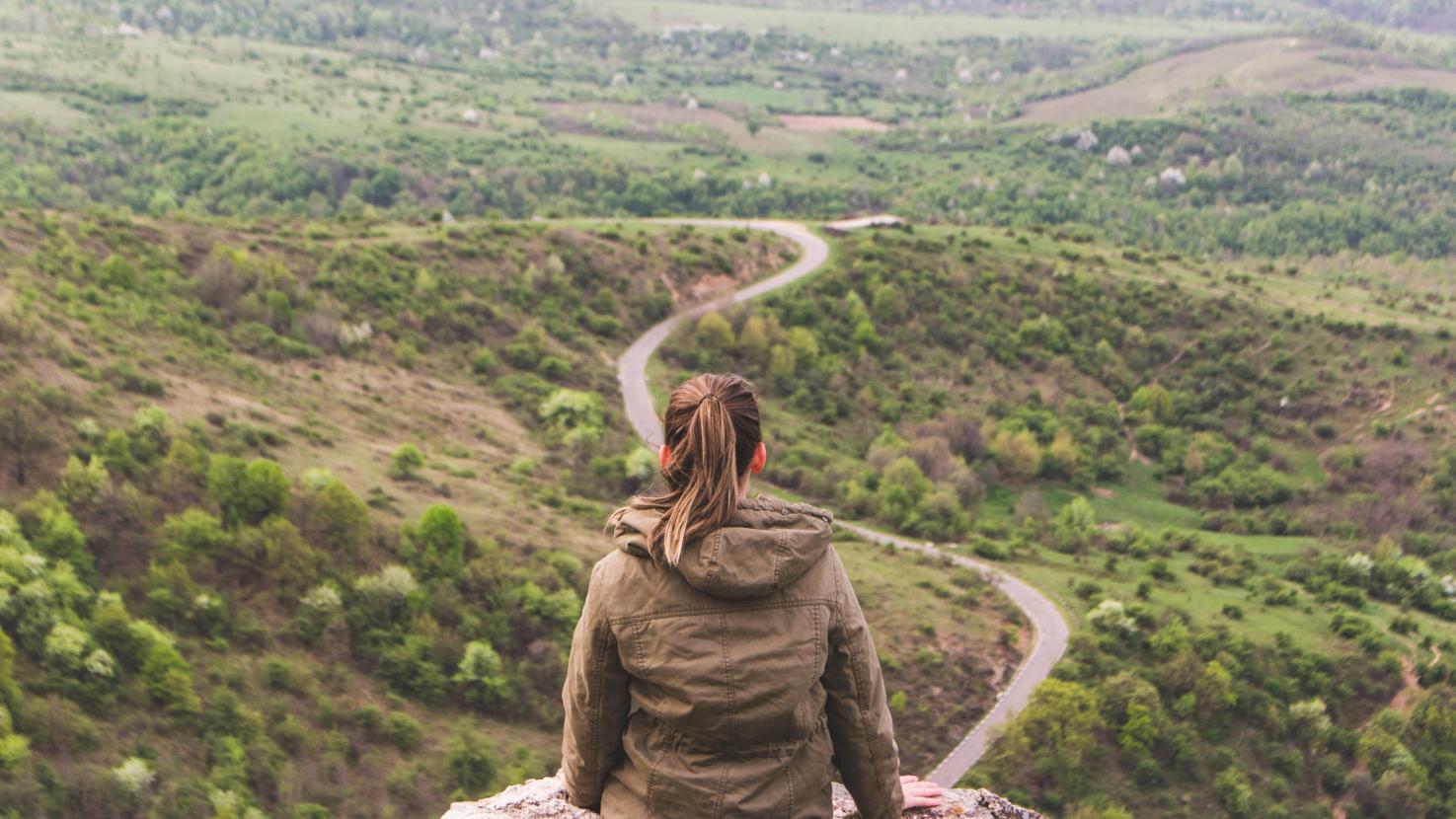 Woman on a hill looking at a long winding path