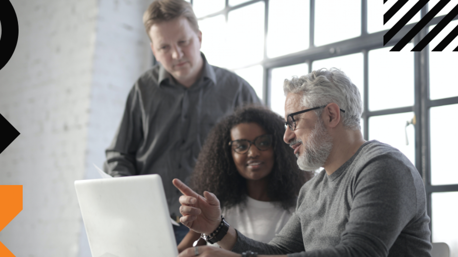 Three coworkers analyzing work on their laptop together