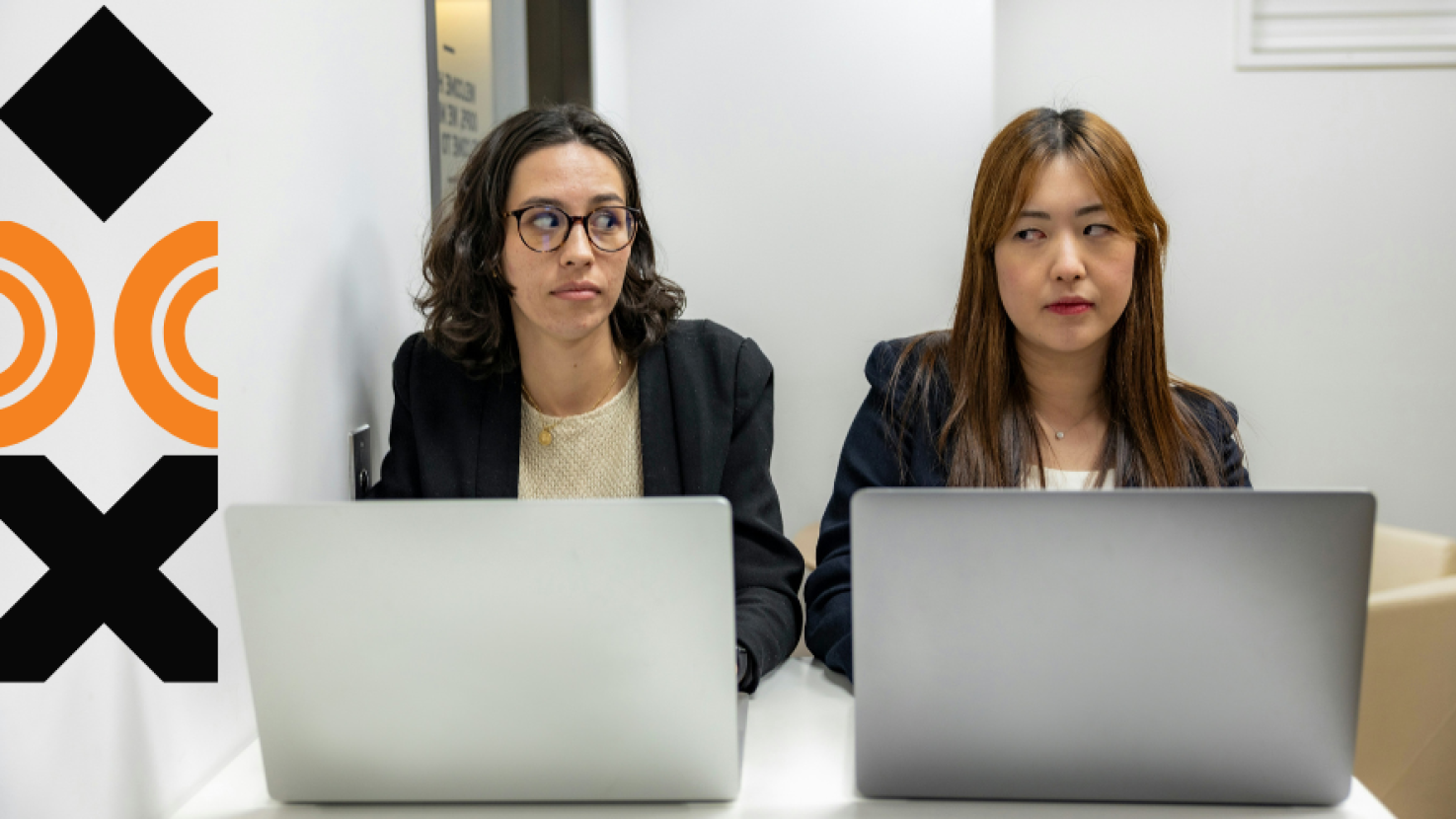 Two coworkers looking annoyed with their laptops