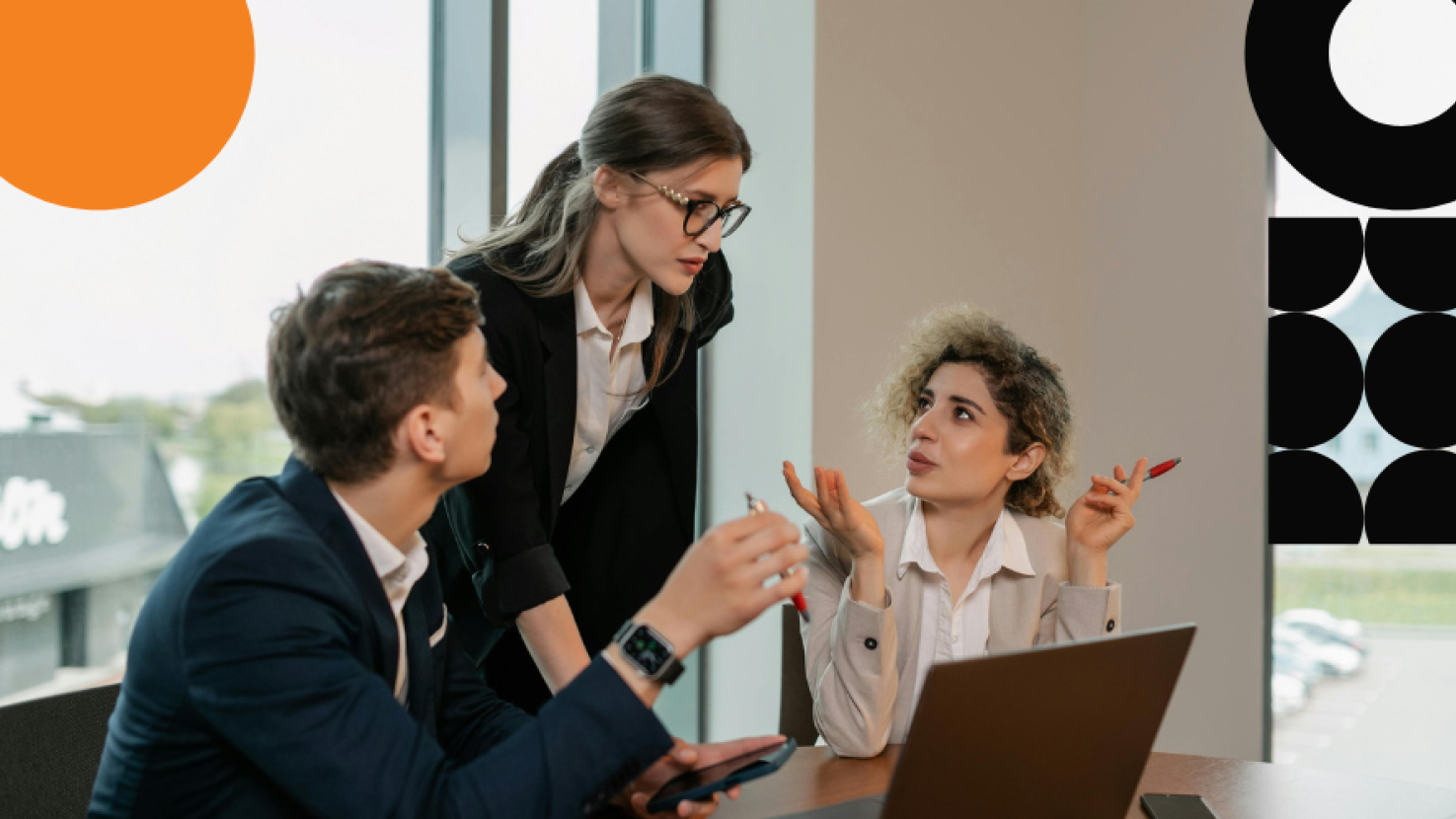Three coworkers discussing around a desk